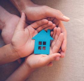 Adult and child hands holding paper house, family home and real estate concept